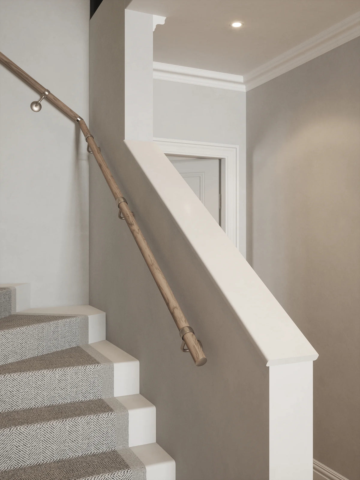 Front view of the Oversley Walnut Single Winder Handrail with Harbury Brushed Silver brackets following the turn of a grey-carpeted staircase.