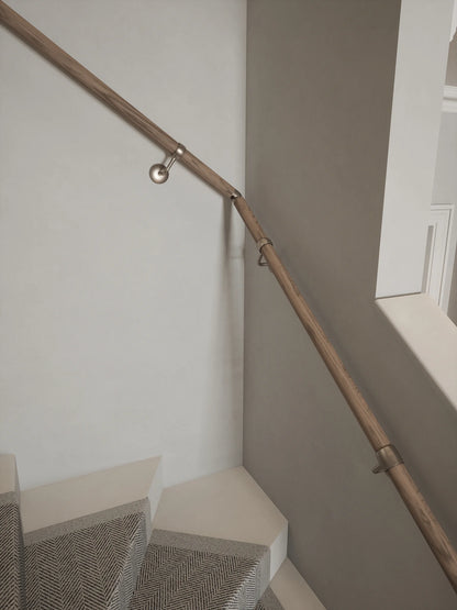Close-up of the Oversley Walnut Single Winder Handrail and Harbury Brushed Silver brackets beside carpeted turning steps.