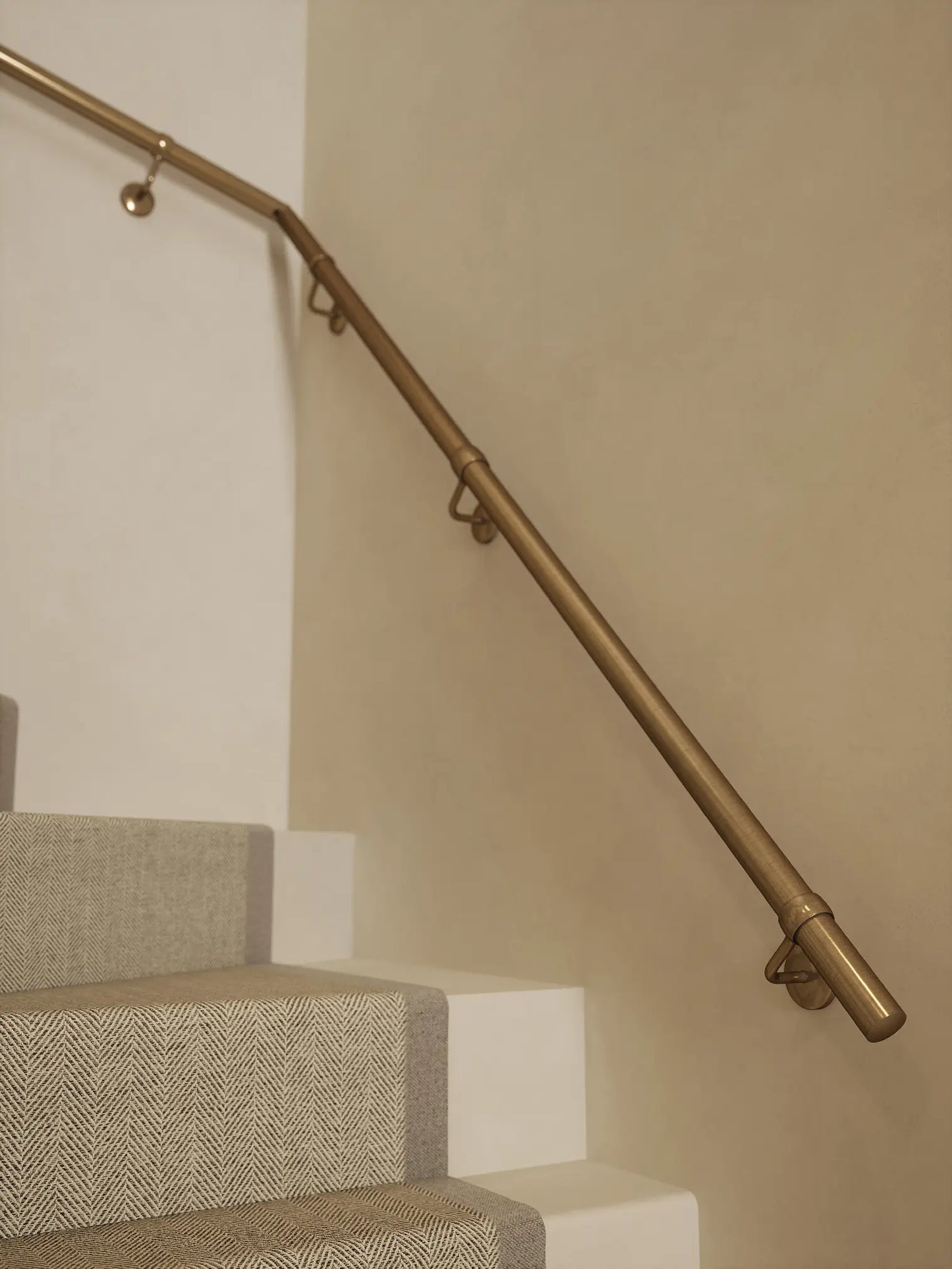Antique brass 40mm double winder handrail mounted on staircase wall, side view