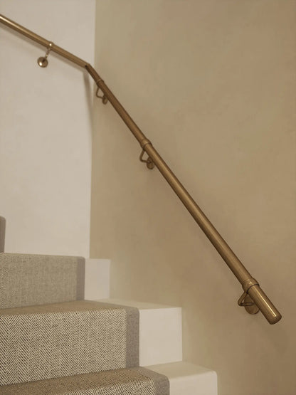 Antique brass 40mm double winder handrail mounted on staircase wall, side view