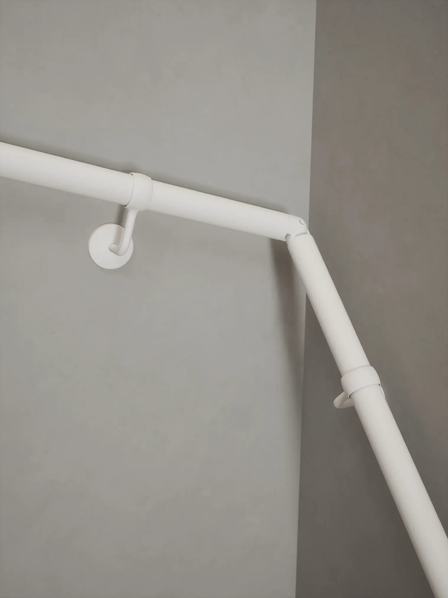 Matt white 40mm double winder handrail, close-up view of angled joint
