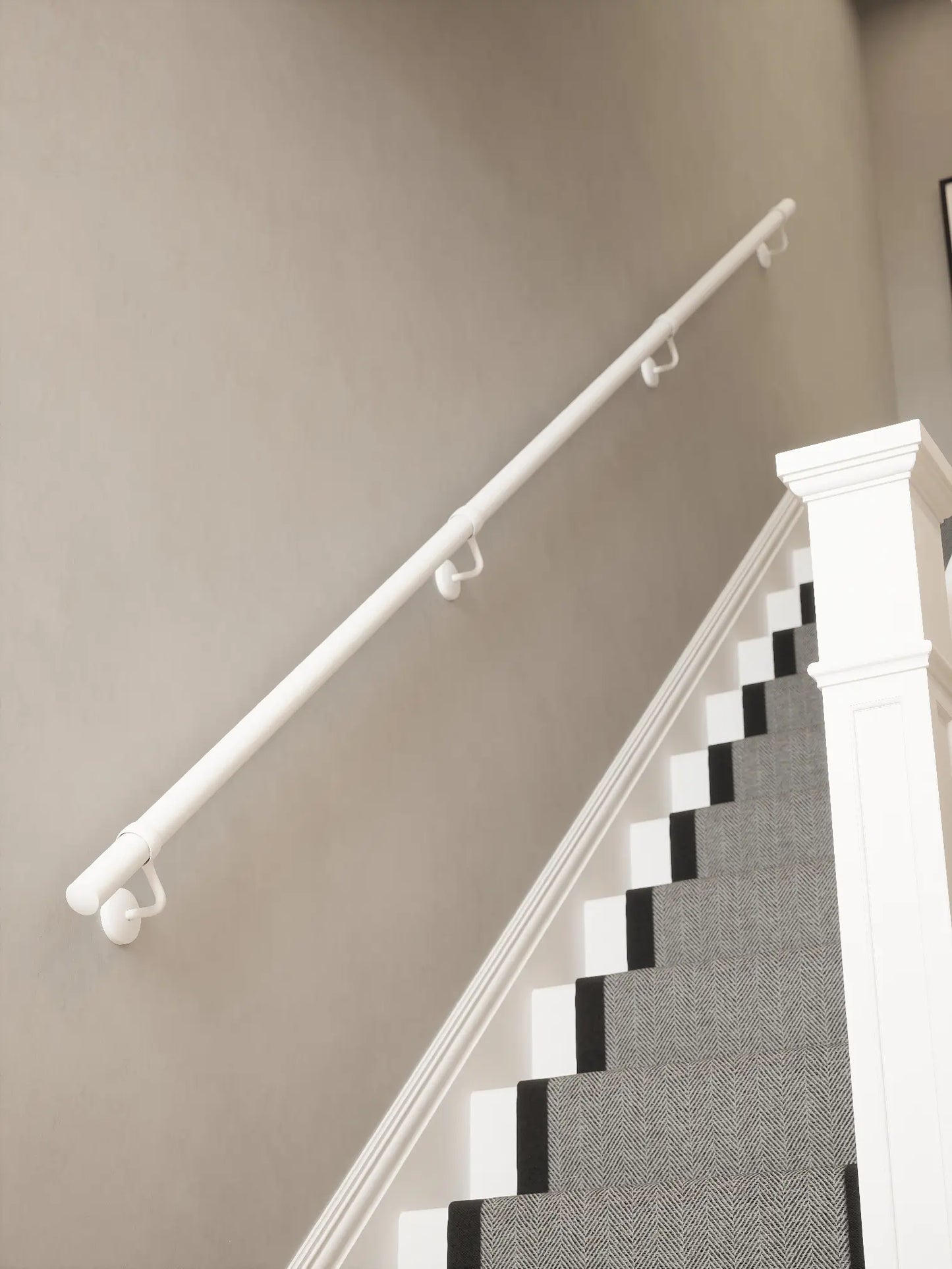 Matt white 3.6m straight run handrail installed on staircase wall, angled view