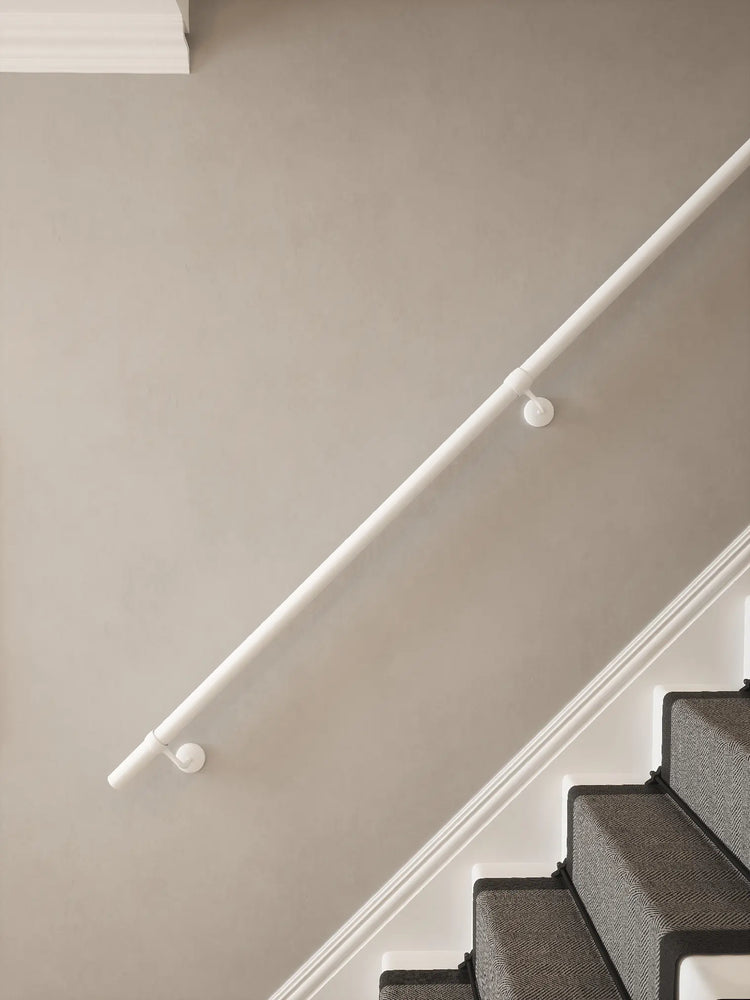 Matt white 40mm straight run handrail mounted on staircase wall, side view