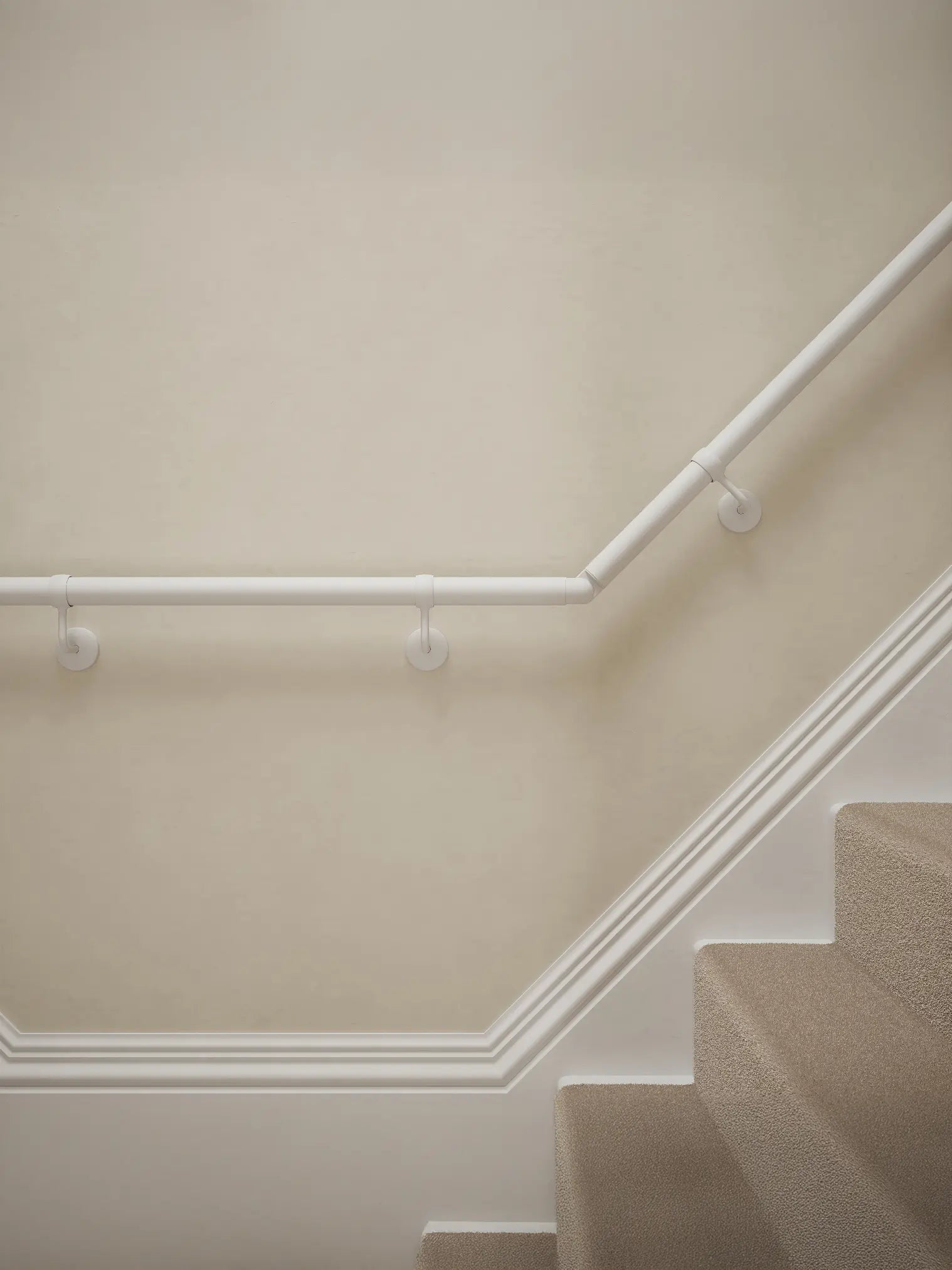 Close-up of Edstone Matt White wall-mounted handrail with brackets on a T-shape staircase – Handrails Direct UK supplier of modular indoor handrails and fittings