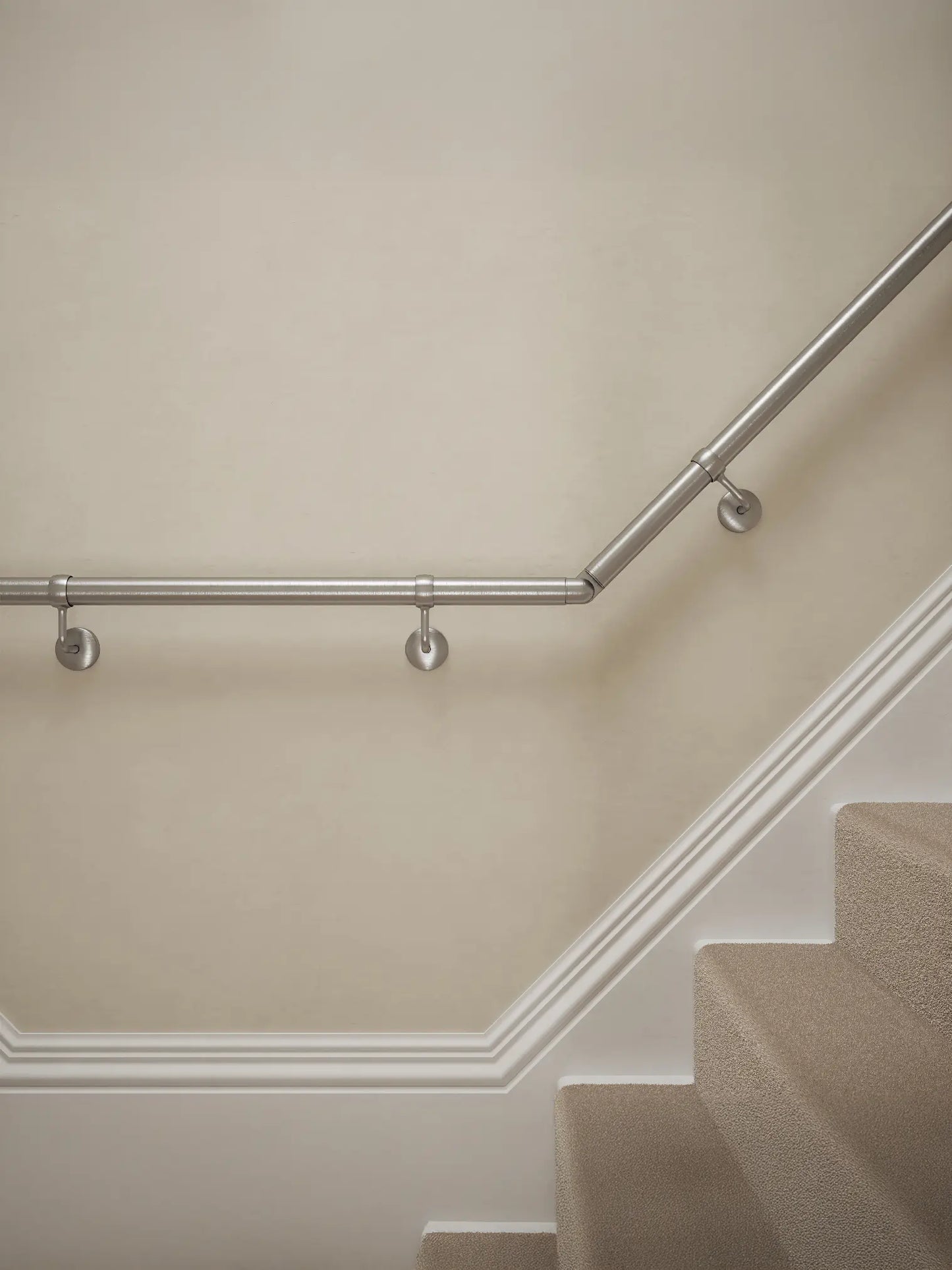 Close-up of Harbury Brushed Silver wall-mounted handrail with brackets on a T-shape staircase – Handrails Direct UK supplier of modular indoor handrails and fittings