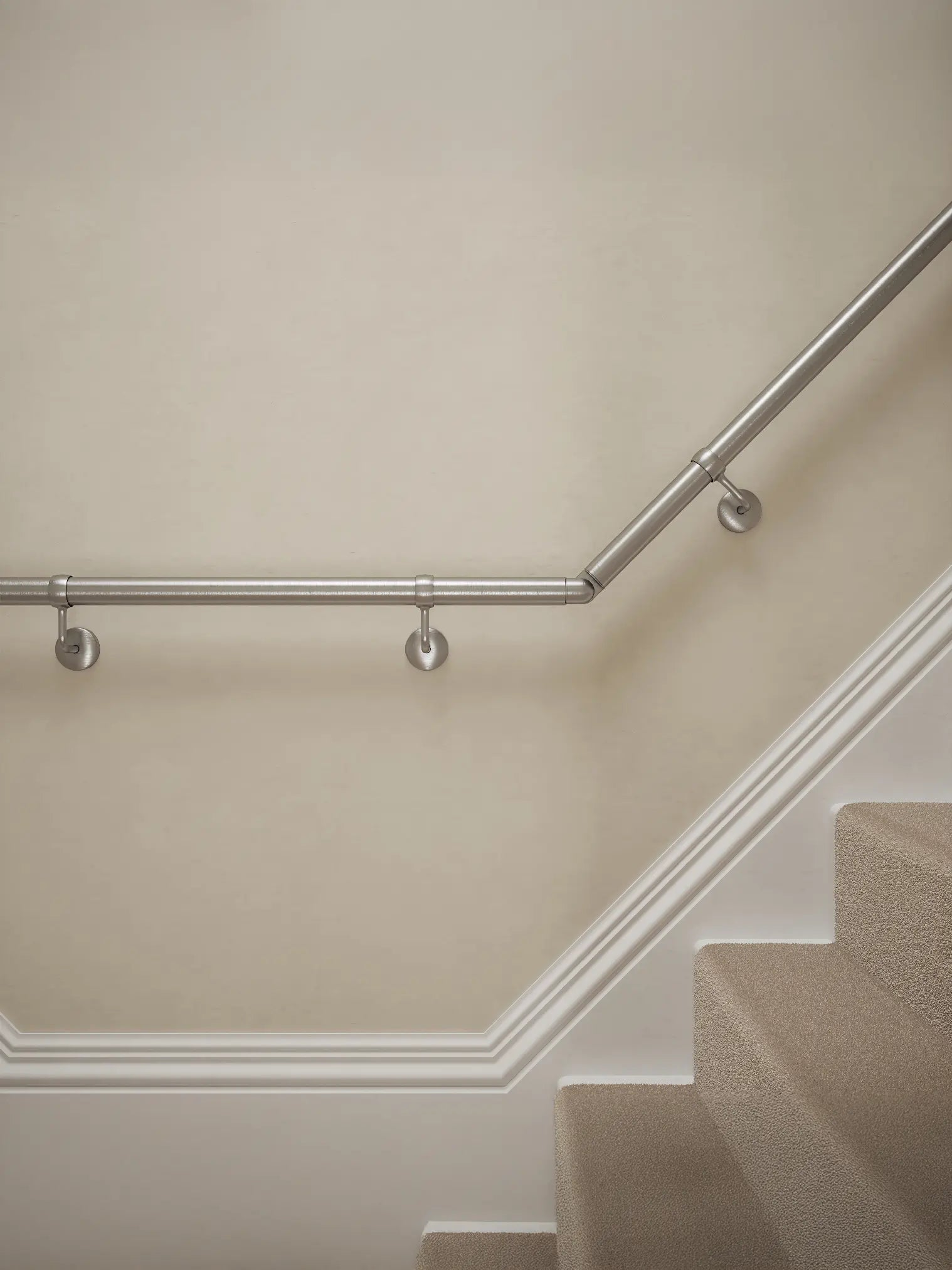 Close-up of Harbury Brushed Silver wall-mounted handrail with brackets on a T-shape staircase – Handrails Direct UK supplier of modular indoor handrails and fittings