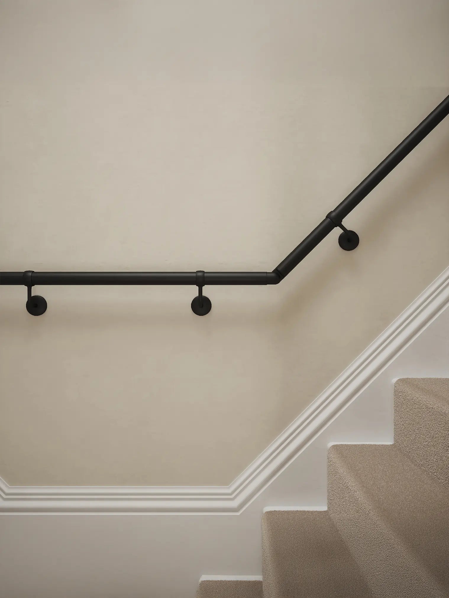 Close-up of Kineton Matt Black wall-mounted handrail with brackets on a T-shape staircase – Handrails Direct UK supplier of modular indoor handrails and fittings