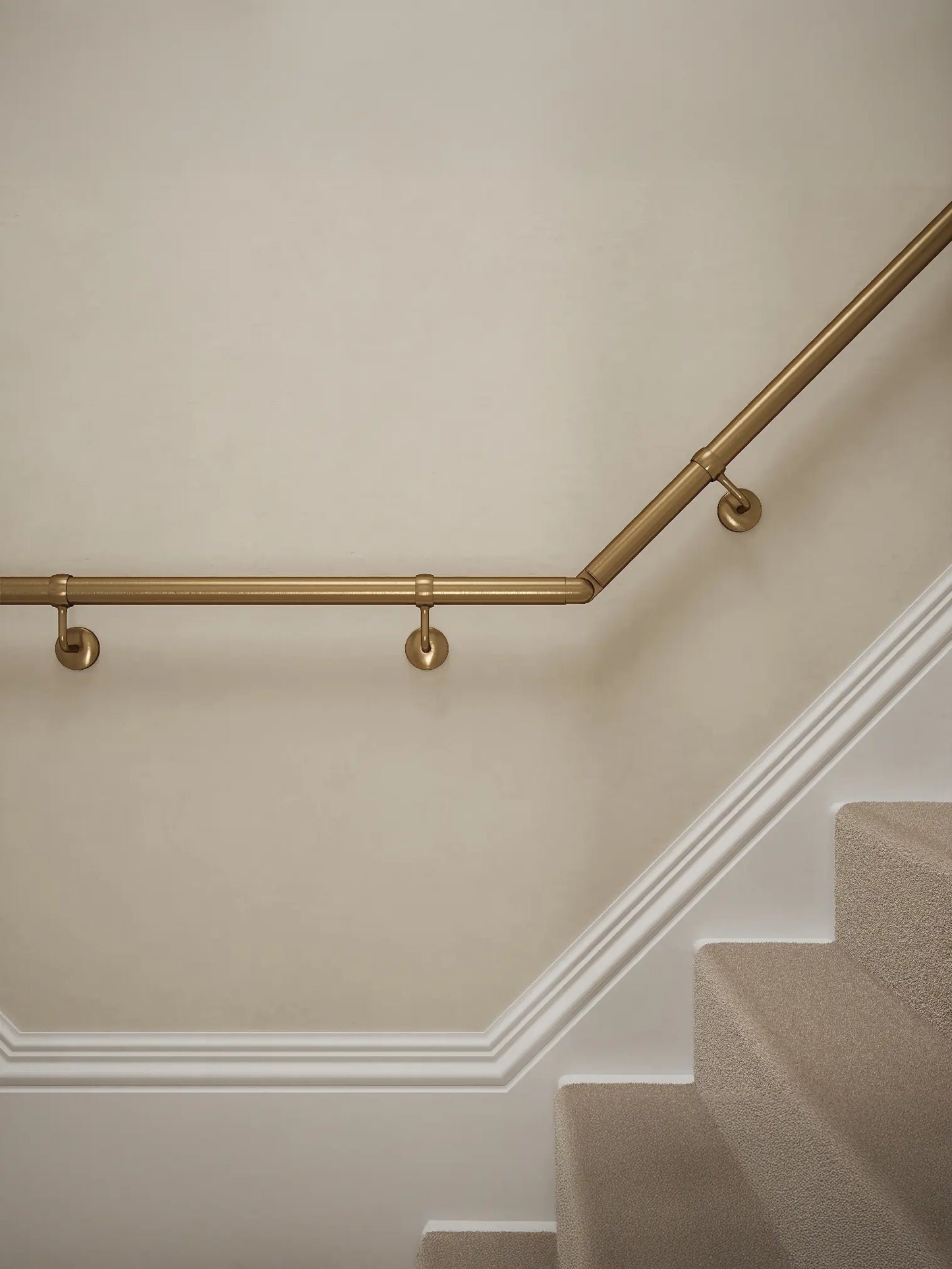 Close-up of Loxley Antique Brass wall-mounted handrail with brackets on a T-shape staircase – Handrails Direct UK supplier of modular indoor handrails and fittings
