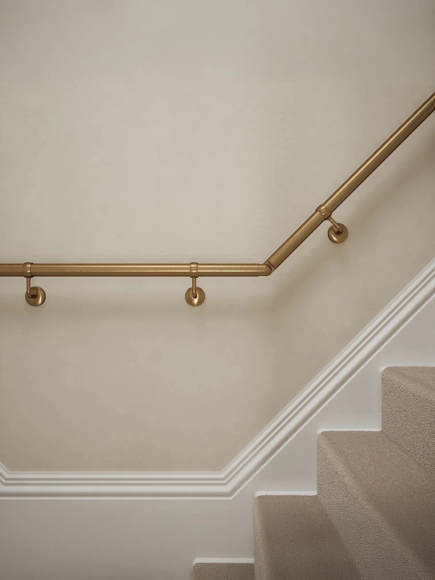 Close-up of Loxley Antique Brass wall-mounted handrail with brackets on a T-shape staircase – Handrails Direct UK supplier of modular indoor handrails and fittings
