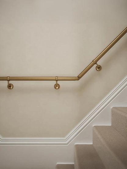 Close-up of Loxley Antique Brass wall-mounted handrail with brackets on a T-shape staircase – Handrails Direct UK supplier of modular indoor handrails and fittings